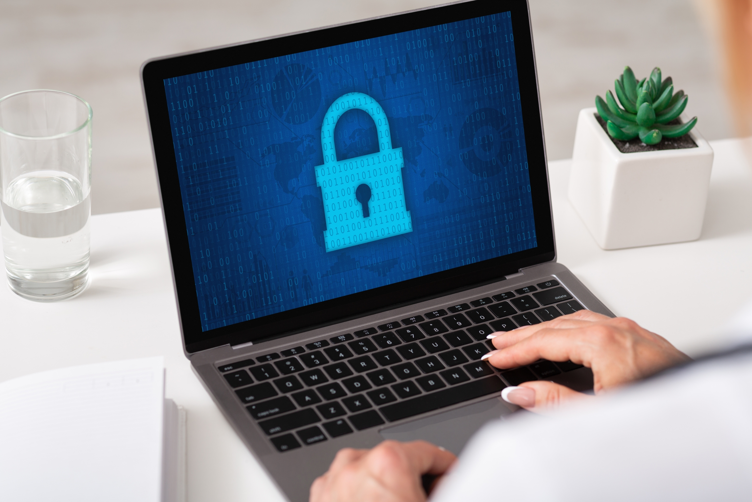 Woman typing on laptop keyboard, padlock icon on the screen